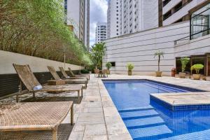 a swimming pool with lounge chairs next to a building at L.A.R. Jardins. Limpeza diária, vaga e bikes in Sao Paulo