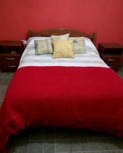 1 cama con manta roja y almohadas en Cabañas Raíces de la Estancia 2 in 