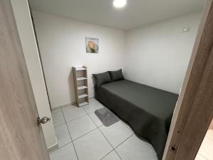 a small bedroom with a green bed and a shelf at Joyful! Medellin Itagüi in Itagüí