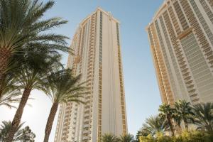 zwei hohe Gebäude mit Palmen im Vordergrund in der Unterkunft No Resort Fee Strip View Suite + Free Valet + Pool in Las Vegas