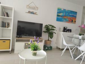 a living room with a tv and a table with flowers at ATLANTERRA PUEBLO in Zahara de los Atunes