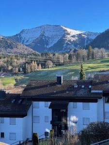 un bâtiment blanc avec une montagne en arrière-plan dans l'établissement BERGfeeling mit Oberstaufen PLUS, à Oberstaufen