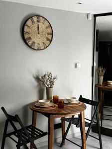 uma mesa de jantar com um relógio na parede em Vizbulu Holiday Home em Kuldīga