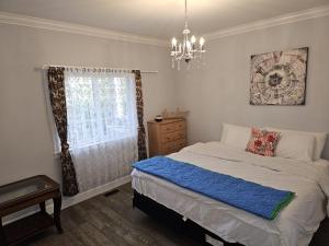 Schlafzimmer mit einem Bett und einem Kronleuchter in der Unterkunft Oscar INN & 2bd Family Suite or Private Room in Abbotsford