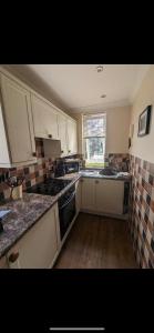 a kitchen with white cabinets and a stove top oven at Chauffeurs Cottage at The Stoep in Paignton