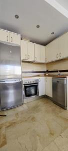 uma cozinha com electrodomésticos de aço inoxidável e armários brancos em 1B Barabas em Mijas Costa