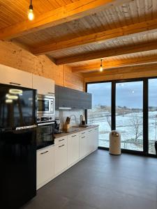 a kitchen with white cabinets and a black refrigerator at Cabana Stil A in Mărişel