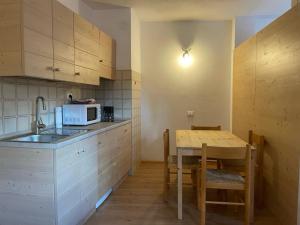a kitchen with a sink and a table with a microwave at Casa Pisolo - presso Sussy Residence in Falcade