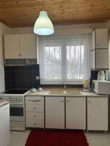 a kitchen with white cabinets and a stove and a window at Chouliarades Tzoumerka in Chouliarades