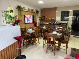a restaurant with wooden tables and chairs and a counter at POUSADA CASA DA CLAUDIA MARAGOGI in Maragogi