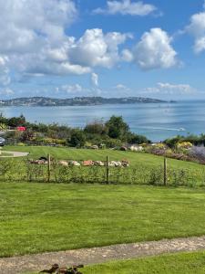 a fence in a field with a view of the water at Chauffeurs Cottage at The Stoep in Paignton