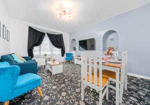 uma sala de estar com uma mesa e cadeiras azuis em Lady Wilson Apartment by Klass Living Airdrie em Airdrie