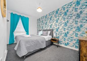 a bedroom with a bed and a blue wall at Lady Wilson Apartment by Klass Living Airdrie in Airdrie