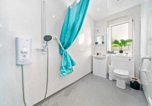 baño blanco con aseo y ventana en Lady Wilson Apartment by Klass Living Airdrie en Airdrie