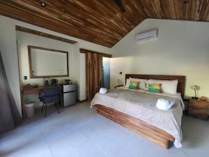 1 dormitorio con 1 cama grande y techo de madera en Villas Pura Vibra en Potrero