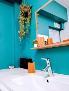 La salle de bains est pourvue d'un lavabo et d'un miroir sur un mur bleu. dans l'établissement Plage & Confort Appartement 3 pièces Parking clim et wifi, à Antibes