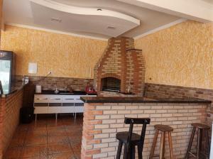 eine Küche mit einem Steinofen und 2 Barhockern in der Unterkunft PousadaRR in Iupeba