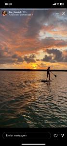 a man riding a paddle board on a body of water at Ekoara Residence in Porto De Galinhas