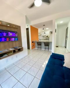 uma sala de estar com um sofá azul e uma cozinha em Apto no Parque dos IPES com 2 Quartos ArCond WiFi Fibra Home Office Garagem em Dourados em Dourados