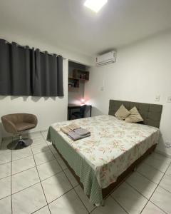 um quarto com uma cama e uma cadeira em Apto no Parque dos IPES com 2 Quartos ArCond WiFi Fibra Home Office Garagem em Dourados em Dourados