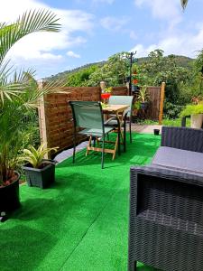 un patio con prato verde, tavolo e sedie di Poz Tropicale a Schœlcher