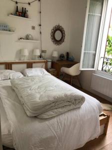 a bedroom with a white bed and a window at Appartement calme et lumineux 4 voyageurs in Malakoff