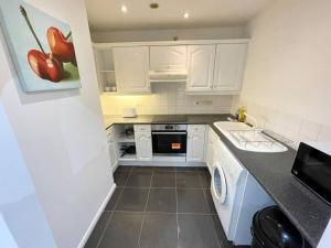 a small kitchen with white cabinets and a dishwasher at Quayside City Escape - Liverpool in Liverpool