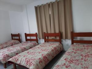 três camas sentadas num quarto com cortinas em Thiferer Hostel em Viçosa