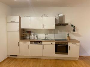 una cocina con armarios blancos y fregadero en Ferienwohnung Bindl, en Ulrichsberg