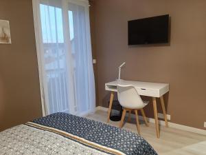 Schlafzimmer mit einem Bett, einem Schreibtisch und einem TV in der Unterkunft Logement tout confort Albi in Albi