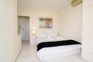 a white bedroom with a bed and a painting on the wall at Blue vibes by Glyfada beach in Athens