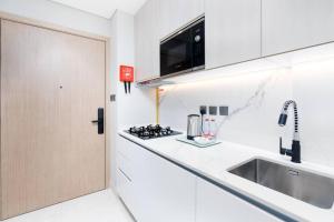a white kitchen with a sink and a microwave at Studio - 3min from Metro station - Westwood by Imtiaz in Dubai