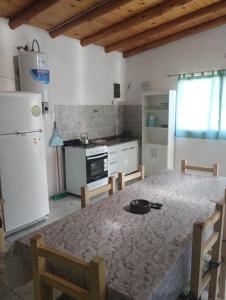 a kitchen with a table and a white refrigerator at Atardecer Serrano in Huerta Grande