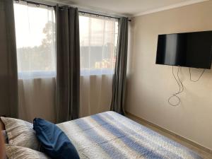 a bedroom with a bed and a flat screen tv on the wall at Departamento en Viña del Mar in Viña del Mar