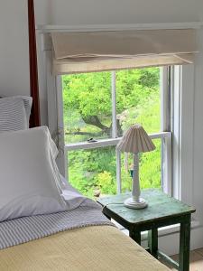 a bed with a lamp on a table next to a window at Marston House Wiscasset in Wiscasset