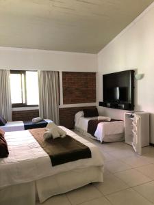 a hotel room with two beds and a flat screen tv at Complejo Laderas del Cerro in Piriápolis +86 photos