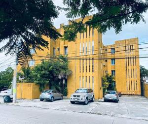 un bâtiment jaune avec des voitures garées devant lui dans l'établissement Zely Home #3, à Cancún
