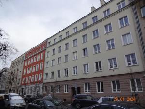 un gran edificio con coches estacionados frente a él en Apartament Wspólna 59 Warszawa, en Varsovia