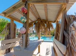 a wooden pergola with a table next to a pool at Beach getaway paradise in Fort Pierce