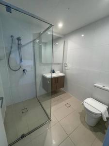 uma casa de banho com uma cabina de duche em vidro e um WC. em Governor Place - Executive Central Apartment em Kingston 