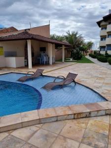 a swimming pool with two chairs and a house at Apartamento Taíba Beach in São Gonçalo do Amarante +4 photos