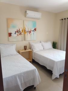 two beds in a room with white sheets at Apartamento Taíba Beach in São Gonçalo do Amarante