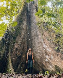 Eine Frau, die vor einem großen Baum steht in der Unterkunft Isla Ecologica Mariana Miller in Puerto Misahuallí