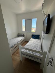 Habitación pequeña con 2 camas y TV de pantalla plana. en Apartamento no Guarujá - Enseada, en Guarujá