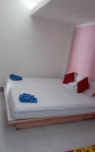 uma pequena cama com lençóis brancos e almofadas vermelhas e azuis em lanta white sand beach guesthouse em Ban Mo Nae