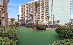a large building with palm trees and a green lawn at One Bedroom Ocean View Condo in Myrtle Beach