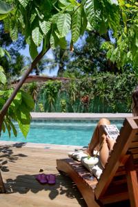 a person laying on a towel next to a swimming pool at Pousada Fruta Pão in Barra Grande