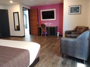 a hotel room with a bed and a chair and a television at Mansion Azul Cholula in Cholula