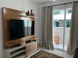 uma sala de estar com uma televisão de ecrã plano num centro de entretenimento em Village blue AC Wi-Fi piscina em Cabo Frio