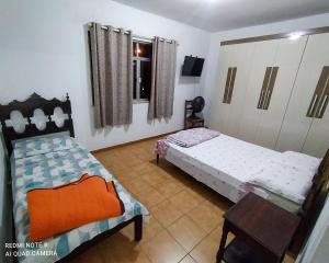 a bedroom with two beds and a table and a chair at Hotel Pousada das Rosas in São Lourenço